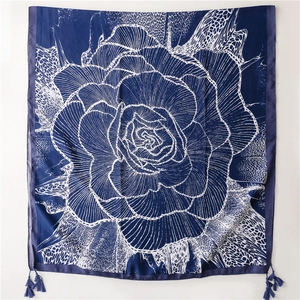 Detail of bohemian scarf with large white rose floral pattern and fringe accents