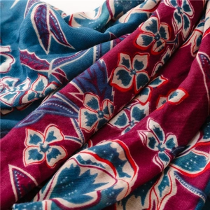 Detail of soft woven scarf showing bold floral print and twill texture in red and blue
