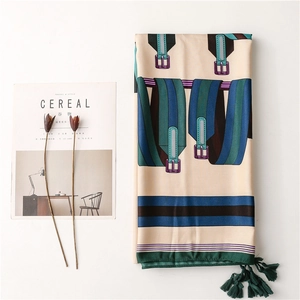 Détail d'un foulard en soie avec imprimé chaîne et pompons vert foncé sur fond blanc