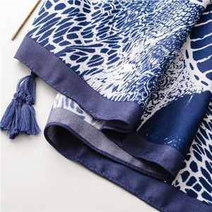 Macro detail of navy blue floral silk shawl showing fabric texture and fringe tassels