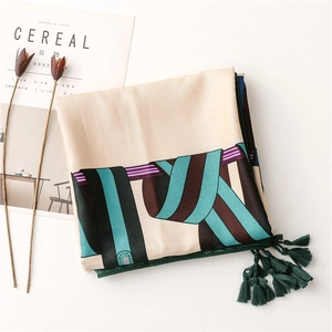 Détail d'un foulard en soie avec motif chaîne, texture corde et glands vert foncé