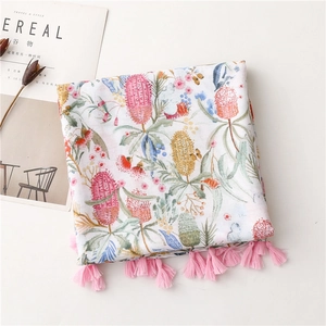 Détail d'une écharpe blanche en coton et lin avec imprimé floral et pompons roses