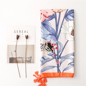 Detailed view of floral silk shawl with blue leaves, pink base, and orange tassels