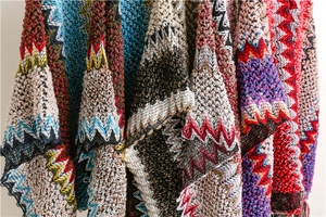 Close-up of thick bohemian knit fabric with colorful zigzag wave patterns on travel shawl