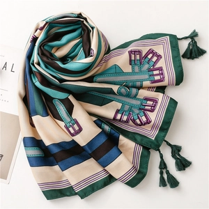 Détail d'un foulard en soie avec motif de harnais classique et finitions à franges vertes