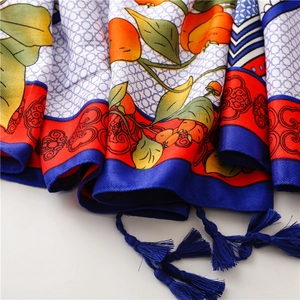 Detail of silk scarf showing vibrant orange prints and elegant blue tassel pendants
