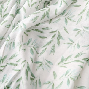 Close-up of lightweight linen scarf featuring fresh green leaf patterns on white fabric