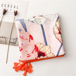 Detailed view of floral print scarf with bright orange tassels and elegant flower patterns