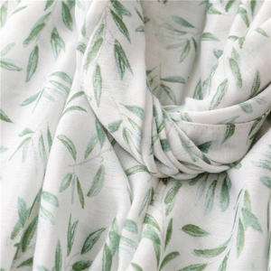 Detailed texture of white linen scarf with elegant green willow leaf print and hemmed edges