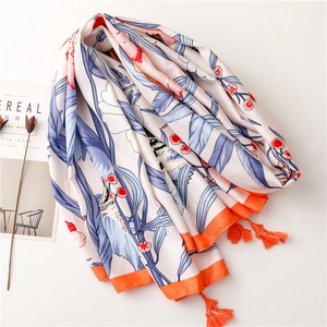 Detail of pink floral silk shawl featuring orange tassels and vibrant botanical prints
