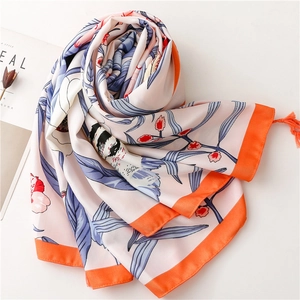 Detailed view of floral silk scarf with vibrant orange fringe and delicate bird print