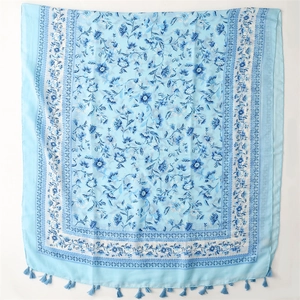 Detail of light blue floral cotton linen scarf featuring vintage patterns and soft tassels