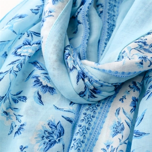 Macro detail of soft light blue floral cotton linen scarf with elegant fringe texture