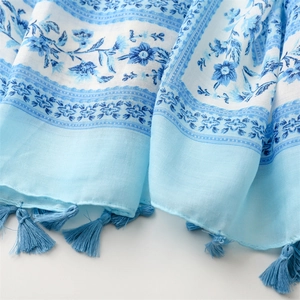Close-up of blue floral cotton linen scarf showing soft fabric texture and fringe tassels