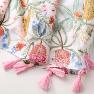 Détail de l'imprimé botanique sur écharpe en coton et lin avec pompons roses