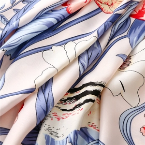 Macro shot of floral silk scarf showing detailed red blooms and soft twill texture