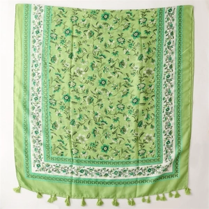Detailed view of light green floral scarf with elegant fringe trim and linen feel fabric
