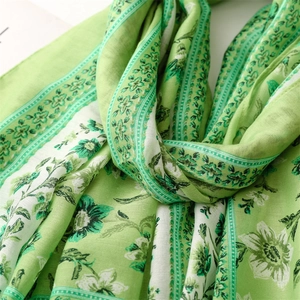 Detailed close-up of light green floral scarf with cotton-linen feel and delicate fringe
