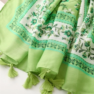 Detail of green floral linen-feel scarf featuring soft tassels and botanical print patterns