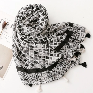 Detail of soft cotton linen scarf featuring grey abstract clover print and fringe edges