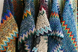 Macro shot of colorful knit poncho fabric showing zigzag patterns and thick wool textures