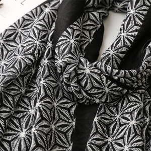 Detail of soft black and white star geometric pattern scarf with elegant draping texture