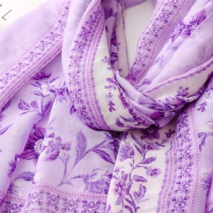 Detailed close-up of soft purple floral linen-feel scarf with delicate tassel textures