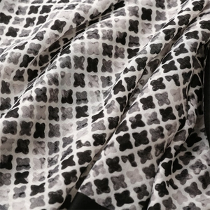 Macro detail of white linen scarf with black cross star pattern and artistic ink texture