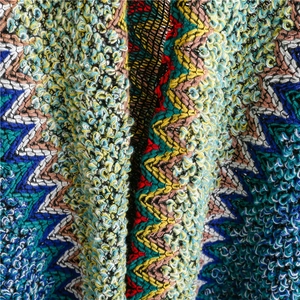 Close-up of bohemian zigzag knit texture with colorful bouclé fabric for travel shawl