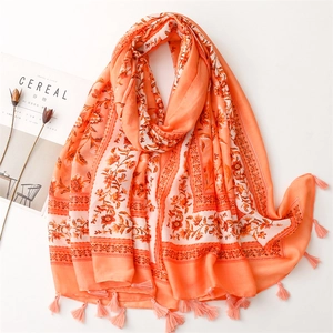 Detailed close-up of orange floral scarf with fringe tassels and soft cotton-linen texture