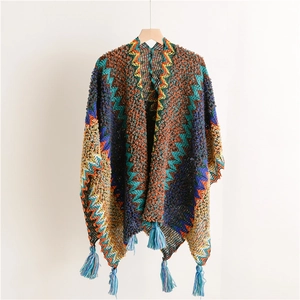 Detail of bohemian knit shawl featuring colorful zigzag patterns and blue fringe tassels