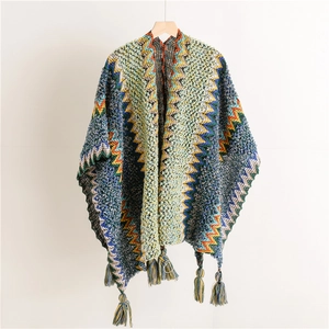 Detail of colorful zigzag knit shawl with decorative tassel fringe on wooden hanger