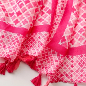 Close-up of pink floral print cotton linen scarf with handmade tassel details and grid pattern
