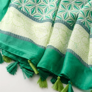 Close-up of green bohemian scarf showing detailed geometric prints and woven fringe tassels