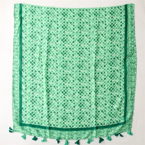 Detail of green scarf with geometric diamond patterns and delicate tassel edges