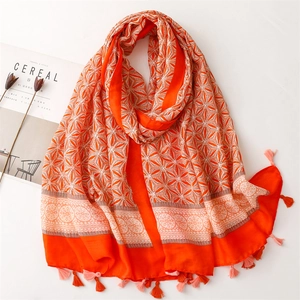 Detail of soft orange linen-feel scarf with white geometric patterns and tassel edges