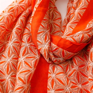 Detail of soft orange floral geometric print scarf with delicate fringe texture