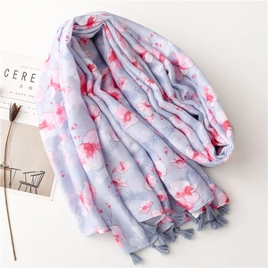 Detail of light blue floral cotton scarf with pink patterns and gray tassel edges