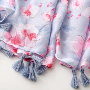 Detail of light blue floral scarf with pink orchid prints and soft fringe tassels