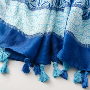 Detailed macro view of the bohemian mandala print and blue tassels on the cotton linen scarf