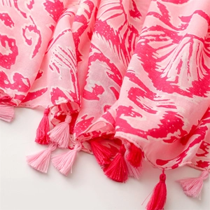 Makro-Detail des weichen rosa Leinenschals mit Fuchsie-Blumendruck und Quasten