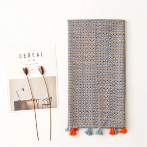 Ethnic geometric print scarf with tassels, styled with a magazine on white background