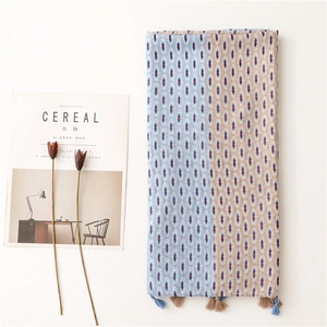 Detail of bohemian geometric scarf with tassel fringe next to a lifestyle magazine