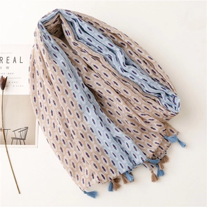 Detail of bohemian scarf with geometric patterns and two-tone tassels on a flat lay
