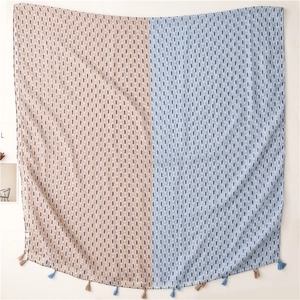 Detail of bohemian scarf featuring blue diamond print, dual-tone fabric and tassel fringe