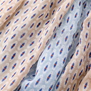 Close-up of bohemian scarf fabric showing blue geometric diamond patterns and soft texture