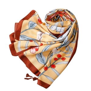 Floral yellow silk shawl with blue leaves and tassels, folded in a spiral arrangement