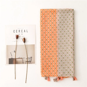 Detailed view of bohemian scarf fabric featuring orange geometric patterns and tassel fringe