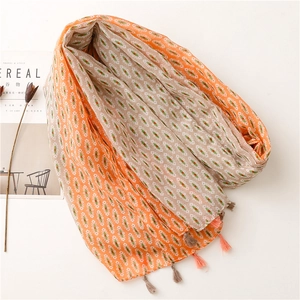 Detail of bohemian scarf featuring orange geometric patterns and delicate fringe tassels