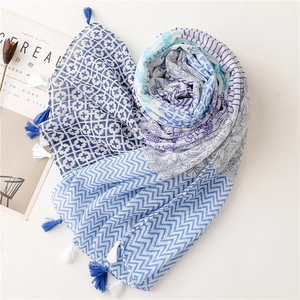 Blue geometric print scarf with tassels and floral patterns on a minimal white backdrop
